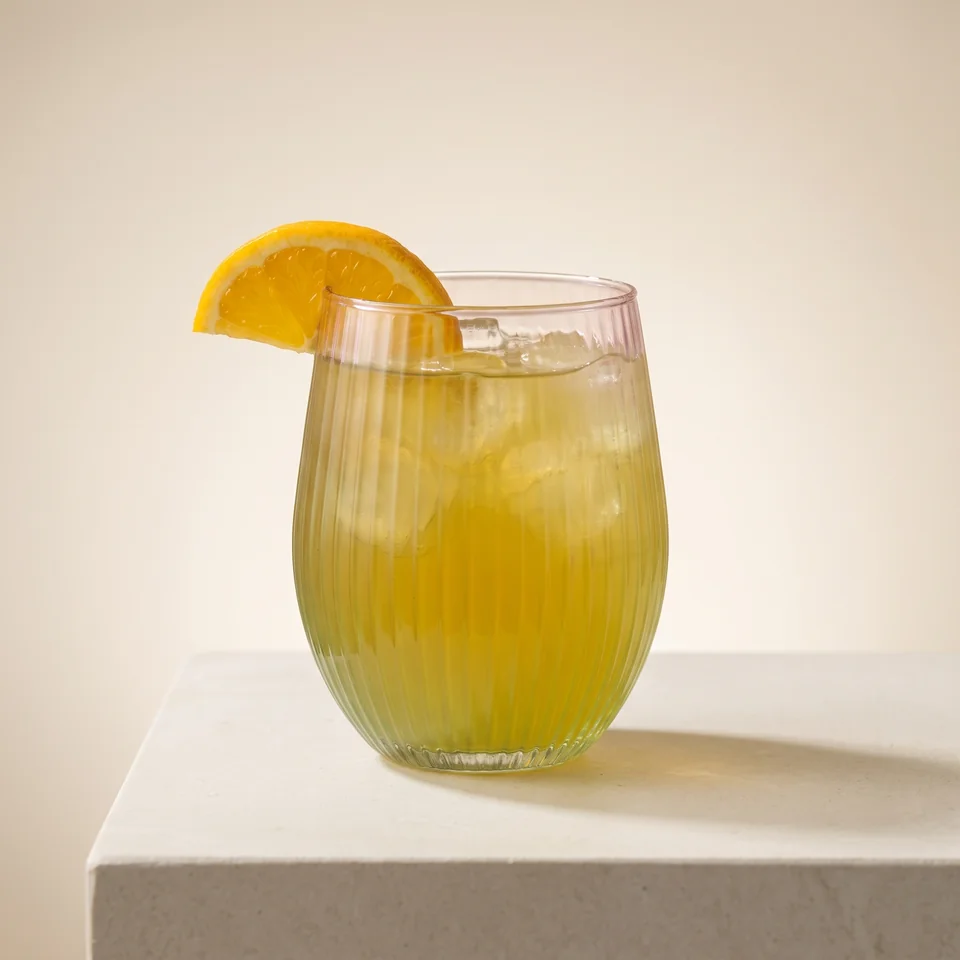 Homemade iced tea with ice cubes and an orange slice on the rim.